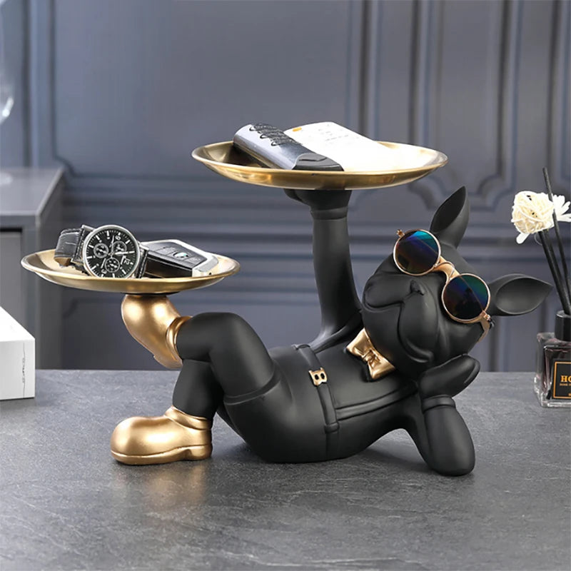 Black and gold dog-shaped jewelry stand with remote control, phone, and watch on a gray surface.