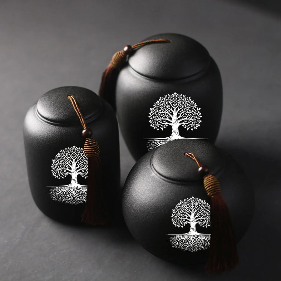 Three black urns with tree designs on a dark background