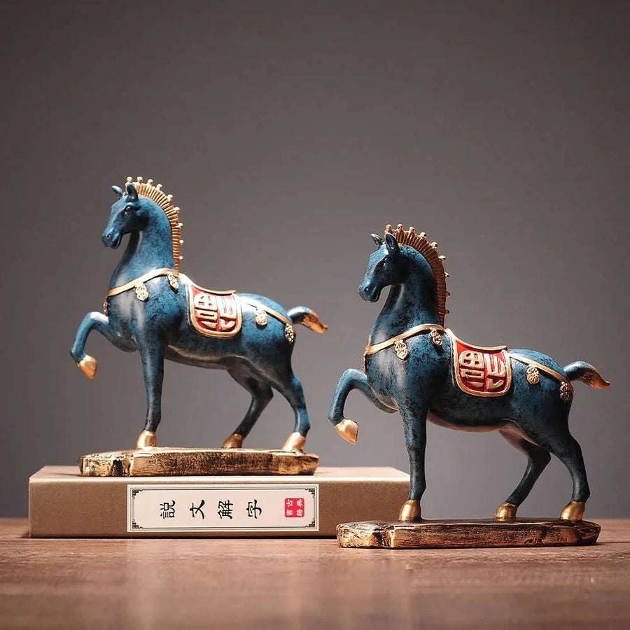 Two blue horse statues with gold accents on a wooden base against a dark background