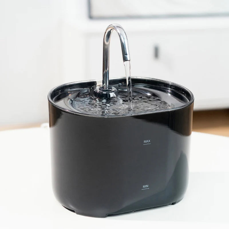 Black pet water fountain on a white surface with water flowing.